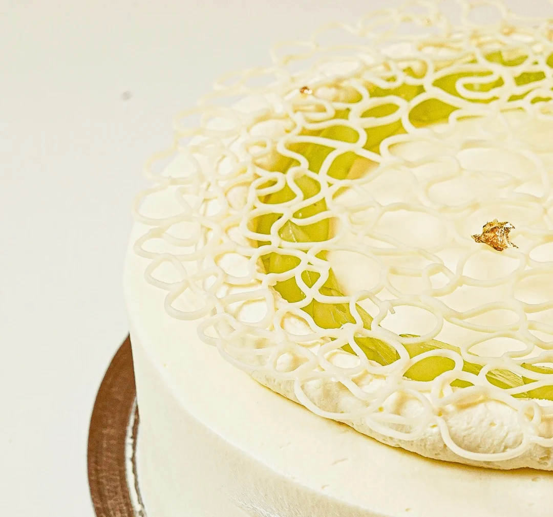 Bolo Pilar da AMAY com cobertura clara e decoração delicada de uva verde