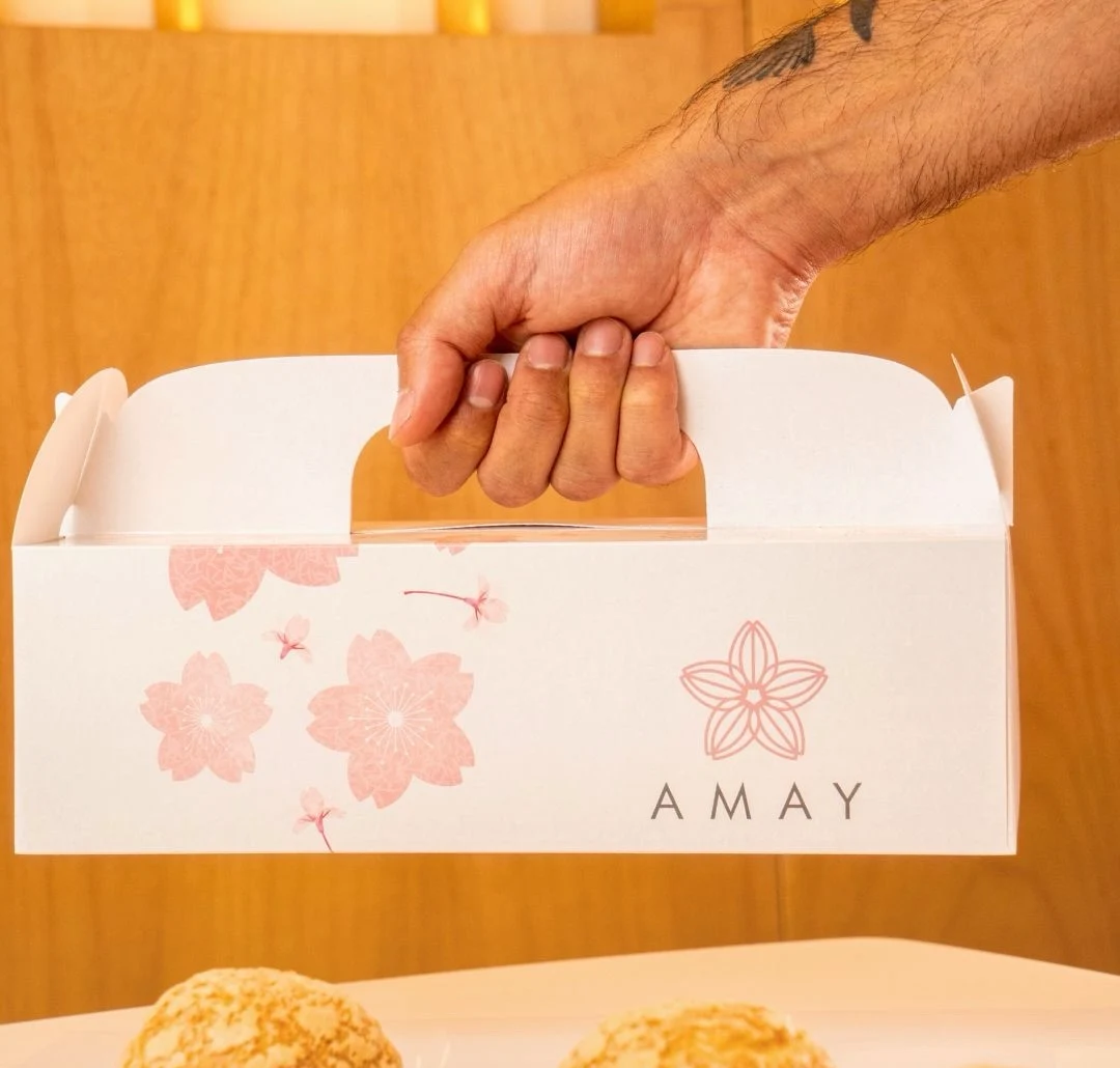 Embalagem real da AMAY com alça e estampa rosa, acompanhada de choux cream